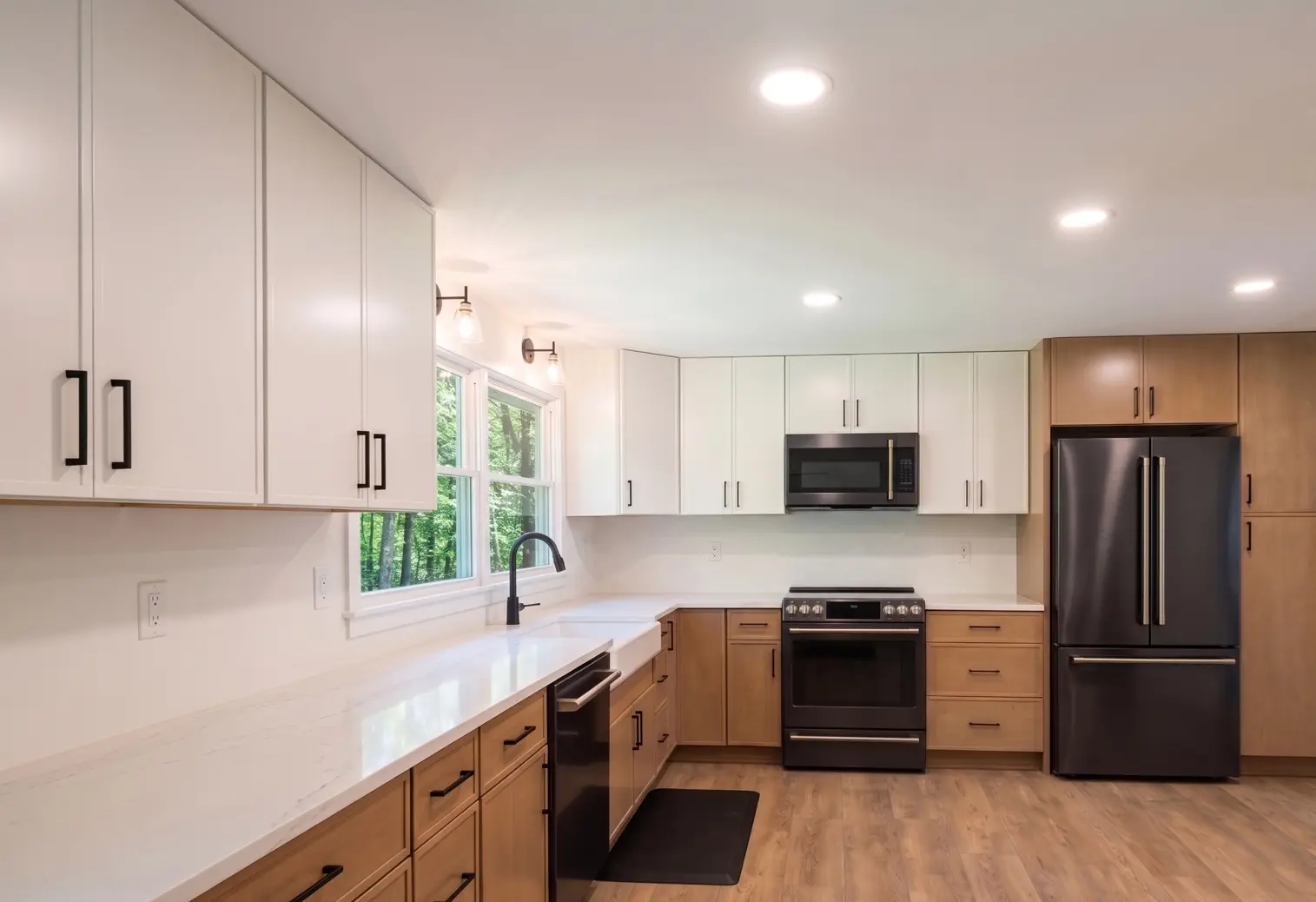 Completed kitchen renovation with two-tone cabinetry and black appliances